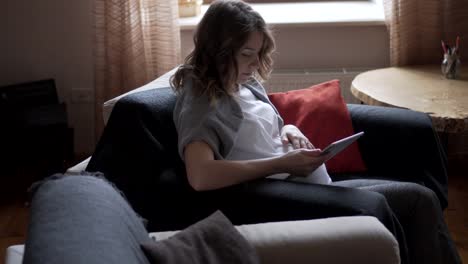 Pregnant-woman-watching-media-content-on-digital-tablet