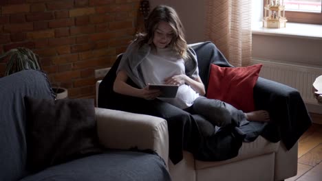 Pregnant-woman-watching-media-content-on-digital-tablet-at-home