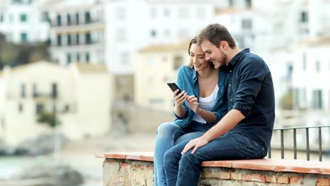 Couple-browsing-on-phone-on-a-ledge