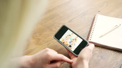 Attractive-Blond-Woman-Swiping-Through-Family-Album-On-Smart-Phone