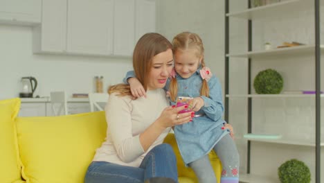 Madre-y-linda-chica-navegando-en-línea-en-el-teléfono-móvil