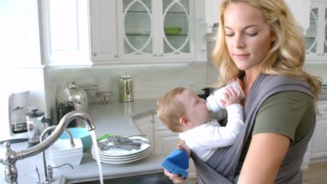 Busy-Mother-With-Baby-In-Sling-At-Home,-Slow-Motion