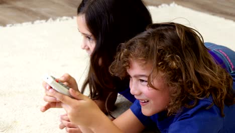 Brother-and-sister-lying-on-the-floor-using-remote-control