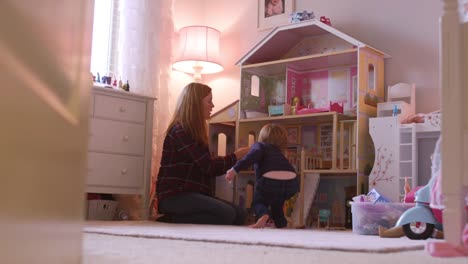 Una-niña-y-su-mamá-jugando-con-una-casa-de-muñecas-gigante-en-su-cuarto