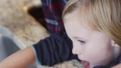 A-mother-helping-her-daughter-wash-her-hands-in-the-kitchen-sink