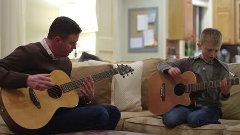 Father-and-son-practicing-on-their-guitars-in-the-living-room