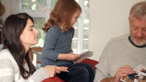 Mehrgenerationenfamilie-zu-Hause-mit-Blick-auf-Fotos