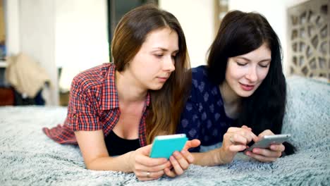 Two-happy-women-friends-sharing-social-media-in-a-smart-phone-and-talking