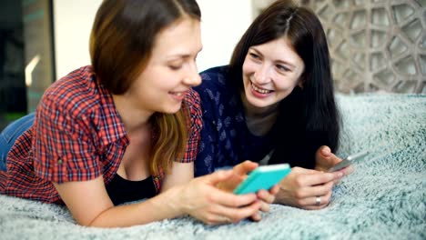 Two-happy-women-friends-sharing-social-media-in-a-smart-phone-and-talking