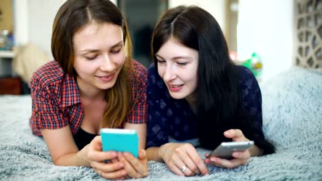 Zwei-glückliche-Frauen-Freunde-teilen-von-sozialen-Medien-in-ein-smart-Phone-und-reden