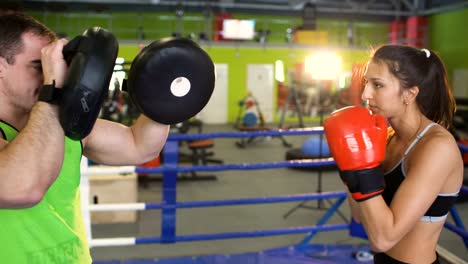 El-entrenamiento-de-la-mujer-joven-boxeador-pre-partido-de-calentamiento-en-el-ring-de-boxeo-con-su-entrenador