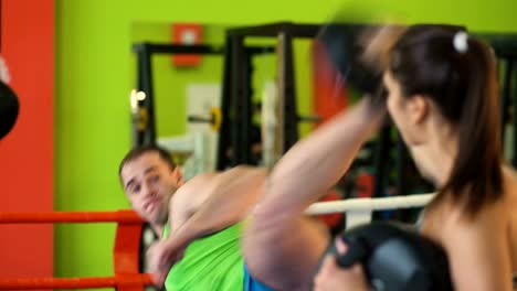 Kickboxing-trainer-man-train-with-young-woman-in-boxing-ring