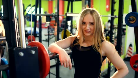 Fuerte-mujer-rubia-atlética-sonriendo-y-mirando-a-la-cámara-en-el-Club-de-fitness