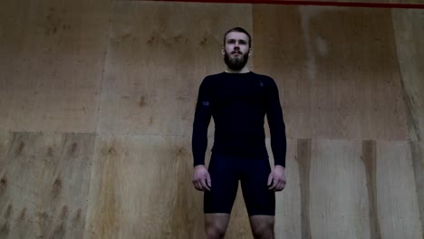 Muskulöser-Mann-Sportler-Portrait-vor-Wand-im-Sportverein-vor