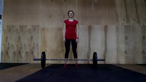 Sportliche-Frau-Athleten-Porträt-vor-Aufhebung-im-Zentrum-glücklich-lächelnd-vor-Gewichte-stehen