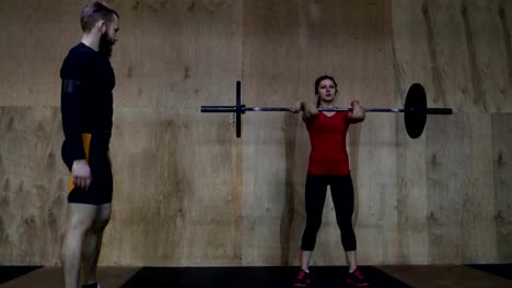 Mujer-atlética,-levantamiento-de-pesas-trabajando-con-Entrenador-Personal-en-gimnasio