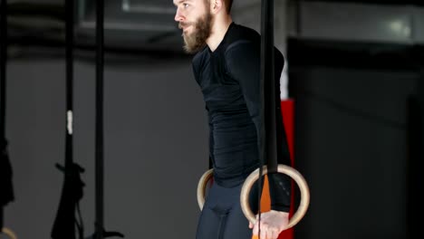 Young-Man-Exercising-On-Gymnastic-Rings-During-Workout-Training-At-Gym