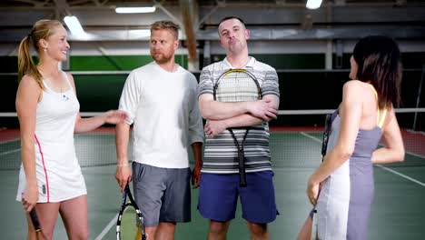 Two-doubles-teams-after-the-tennis-match.-Two-male-players-and-two-female-players.-They-standing-together,-smiling-and-laughing.-Friendly-competition