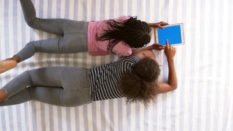 Draufsicht-der-Mädchen-im-Teenageralter-Blick-auf-Digital-Tablette-auf-Bett