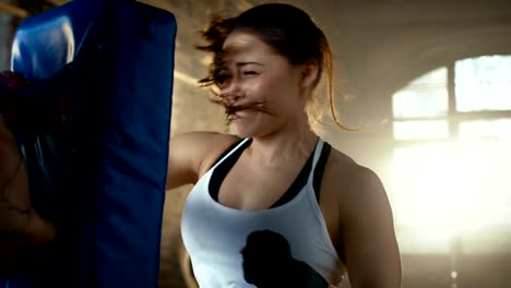 Athletic-Woman-Hits-Punching-Bag-that-Her-Partner/-Trainer-Holds.-She's-Professional-Fighter-and-is-Training-in-a-Gym.