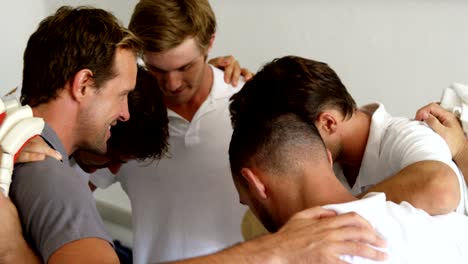 Cricket-team-forming-a-huddle-in-dressing-room