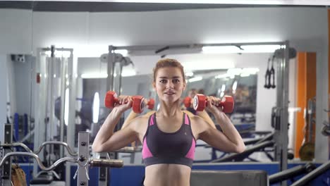 Joven-hermosa-chica-deportiva-haciendo-press-de-hombros-con-pesas-ejercicio-en-un-gimnasio-de-deporte