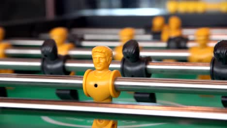 close-up-yellow-players,-young-man-playing-enjoy-foosball-wooden-table-soccer-game