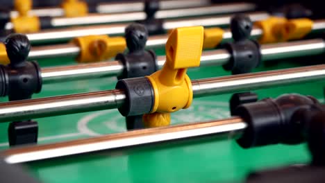 close-up-yellow-players,-young-man-playing-enjoy-foosball-wooden-table-soccer-game