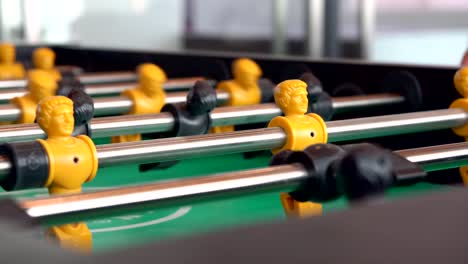 close-up-yellow-players,-young-man-playing-enjoy-foosball-wooden-table-soccer-game