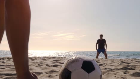 Young-man-goalkeeper-in-swimming-trunks-saves-football-penalty-on-the-sea-shore-at-the-beach-at-sunset-silhouette