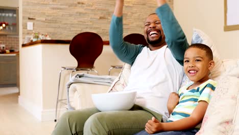 Father-and-son-cheering-up-while-watching-television-in-living-room-4k