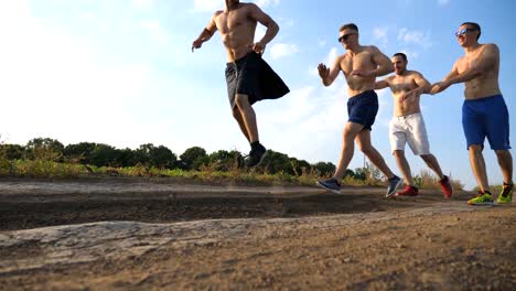 Male-friends-walking-on-country-road-and-having-fun.-Group-of-happy-boys-fool-around-outdoors.-Front-view-Low-angle-view