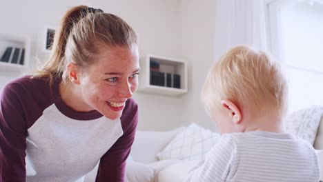 Joven-madre-haciendo-una-cara-al-hijo-de-niño-en-el-hogar