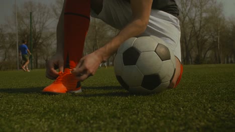 Soccer-player-tying-shoelace-on-football-pitch