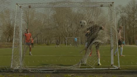 Striker-taking-a-shot-on-goal-during-football-match