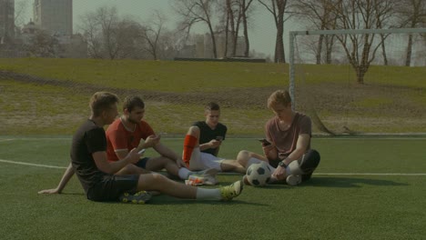 Fußball-Nationalmannschaft-mit-smart-Phones-ruht-auf-Fußballplatz