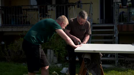 padre-e-hijo-reparacion-las-puertas-de-interiores-en-el-jardín-al-aire-libre