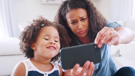 Junge-schwarze-Frau-und-Tochter-nehmen-Selfie-Grimasse