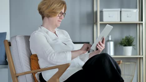 Old-Senior-Woman-Browsing-Internet-on-Tablet-PC,-Sitting-on-Couch