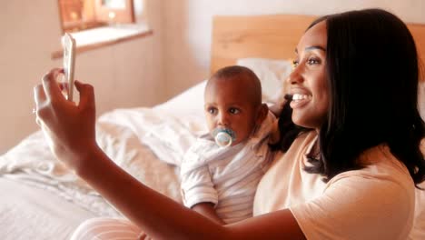 Mother-with-baby-son-video-chatting-on-smartphone-at-home