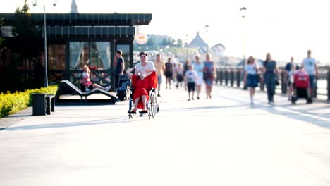 Guy-Rolls-A-Happy-Disabled-Girl-In-A-Wheelchair-On-The-Waterfront