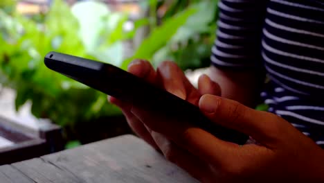 Frau-Hand-mit-Smartphone-im-Café-Shop-Hintergrund.-Wirtschaft-und-soziale-Netzwerk-Konzept.