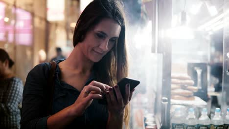 Feliz-CEO-mujer-atractivo-smartphone-aplicación-de-e-commerce-cerca-vapor-vendedor-de-comida-callejera-en-Nueva-York-de-noche