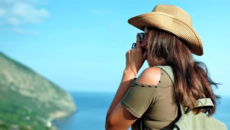 Mujer-fotógrafo-tomar-fotografía-de-paisaje-marino-en-puesta-del-sol-usando-profesional-cámara-vintage