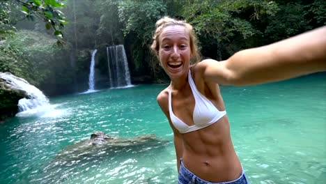 Junge-Frau-unter-Selfie-Porträt-mit-einem-wunderschönen-Wasserfall-auf-der-Insel-Cebu-in-den-Philippinen.-Die-Leute-reisen-Natur-Selfie-Konzept.-Eine-Person,-die-nur-genießen,-Natur-und-Ruhe-in-einer-friedlichen-Umgebung-Slow-Motion-video