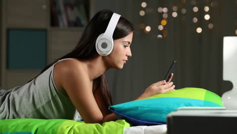 Teen-Musikhören-mit-Kopfhörer-und-Telefon-auf-einem-Bett