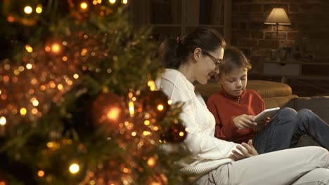 Niño-y-su-madre-utilizando-una-tableta-digital-juntos-en-Navidad