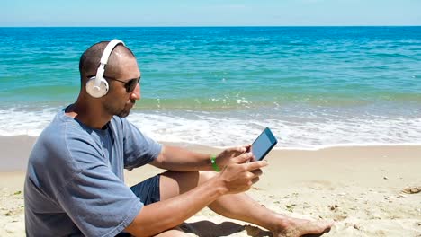 Ein-Mann-mit-einem-Tablet-am-Strand.