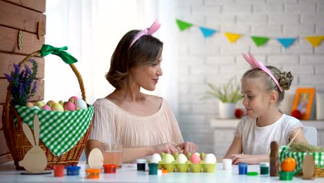 Cheerful-mother-and-daughter-preparing-for-Easter-playing-with-decorated-eggs