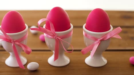 pink-easter-eggs-in-holders-and-candies-on-table